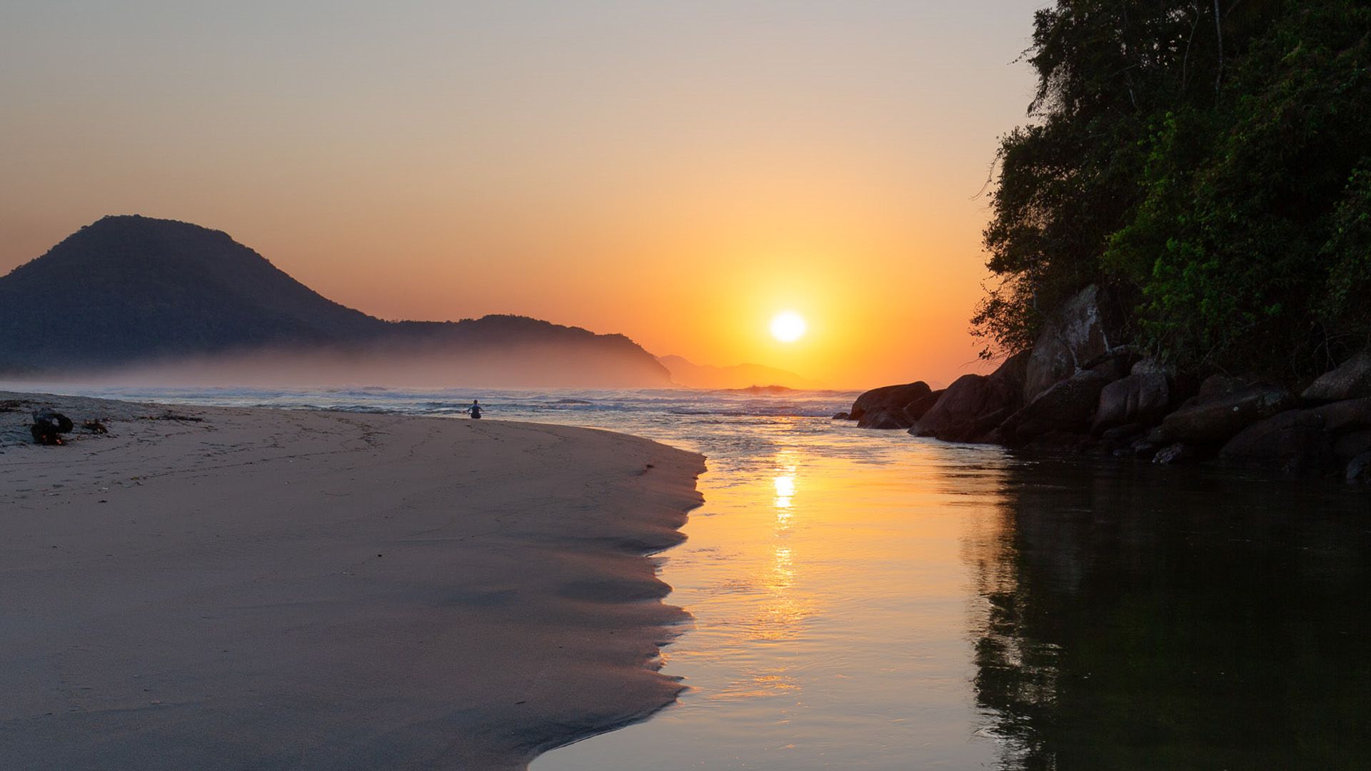 Vista do rio desaguando no mar da Praia de Itamambuca com o sol nascendo ao fundo